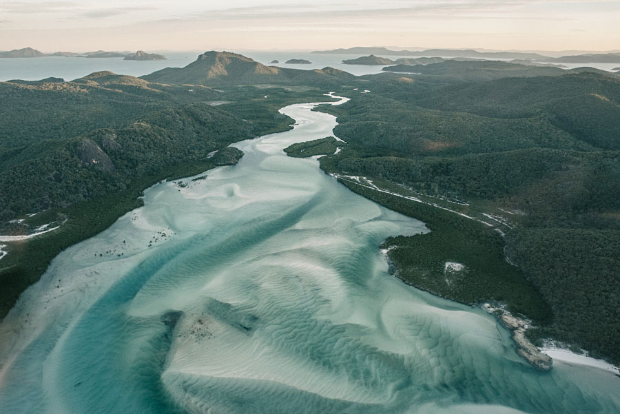 Aerial view of turquoise tidal channels winding through forested green islands