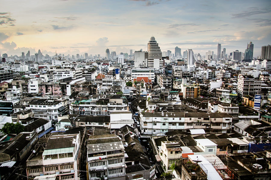Dense urban rooftop view of Bangkok with skyscrapers rising in the hazy distance