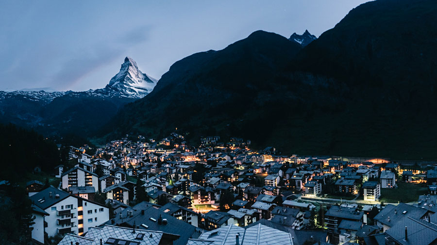 Village of Zermatt glowing at dusk with the Matterhorn rising behind in Switzerland