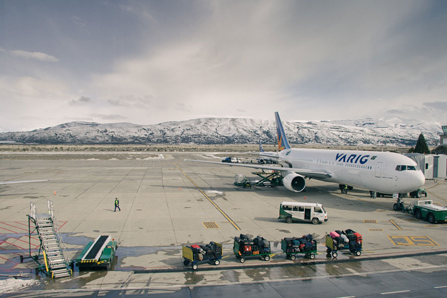 Commercial aircraft parked on the tarmac at an airport with snow-capped mountains behind