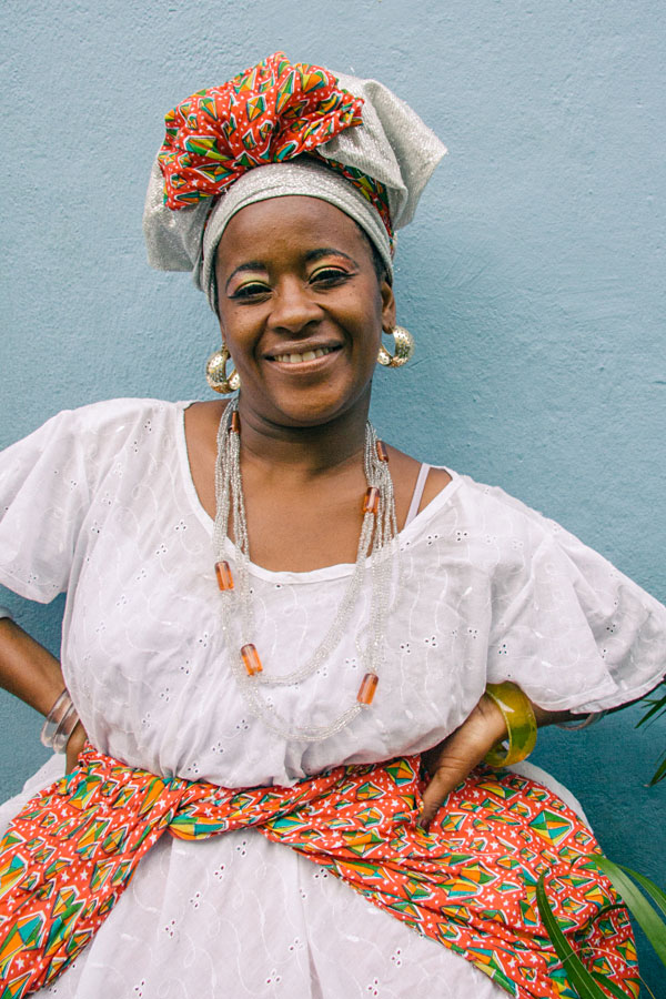 Smiling Brazilian woman in traditional Bahiana dress with colorful headwrap and jewelry