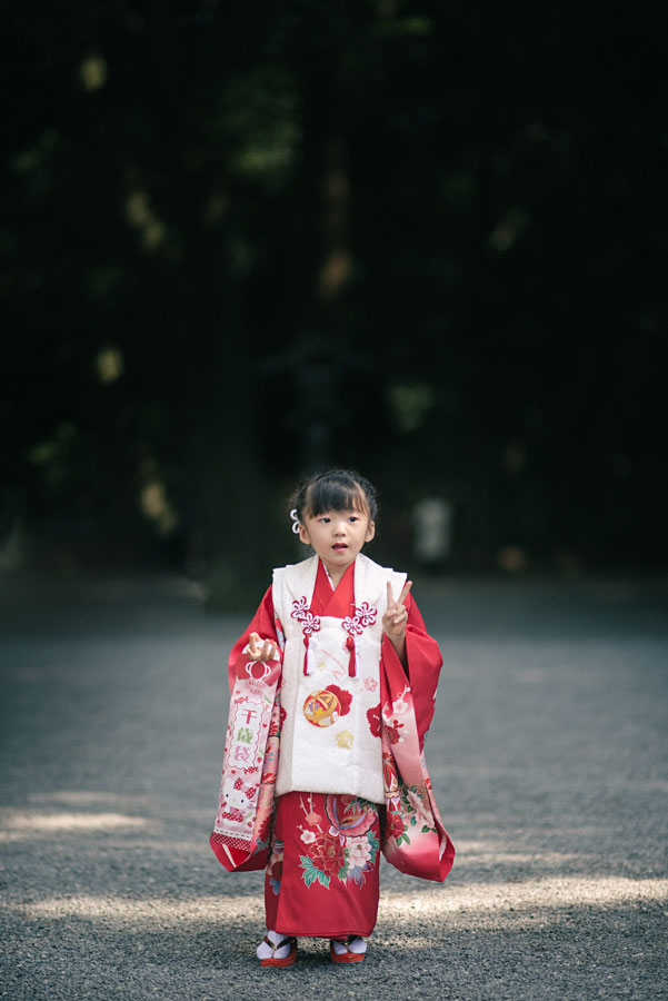 Young girl in a red and white kimono holding a Chitose Ame bag at a Japanese shrine
