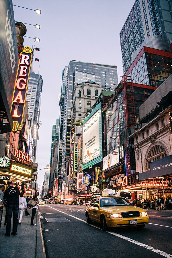 Yellow taxi and neon signs on a busy Times Square street in New York City