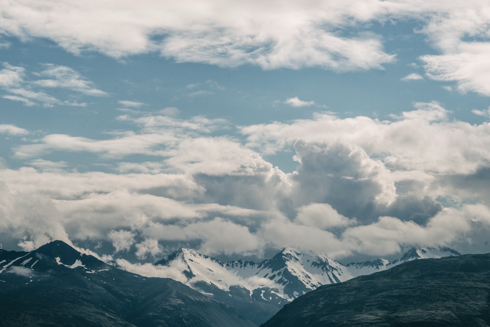 Snow-capped Icelandic peaks emerging through layered cloud, Iceland