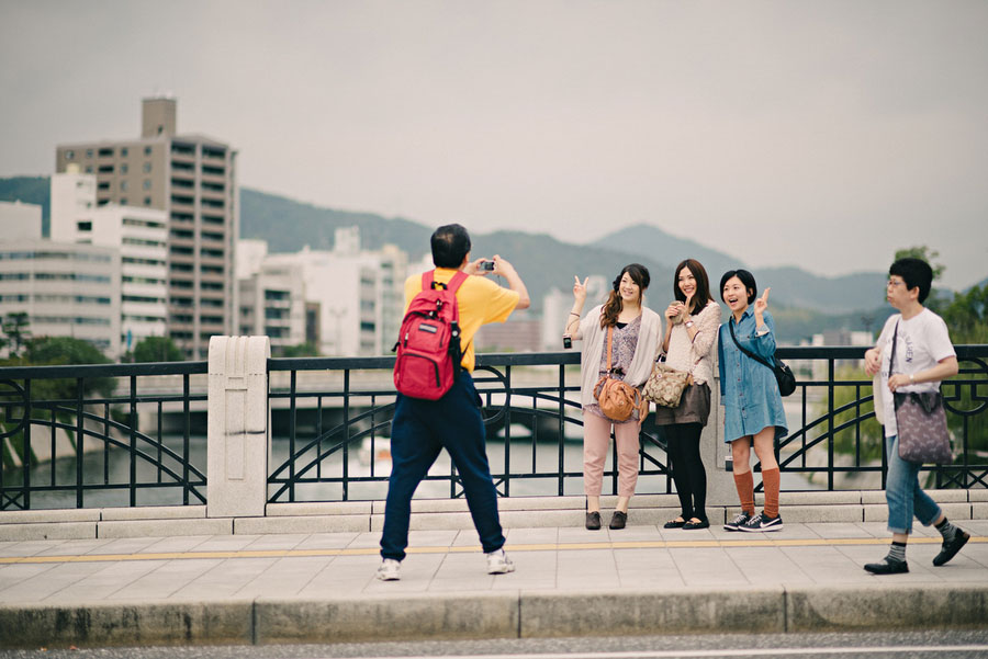 Group of young women posing for a photo on a bridge in Hiroshima with mountains behind