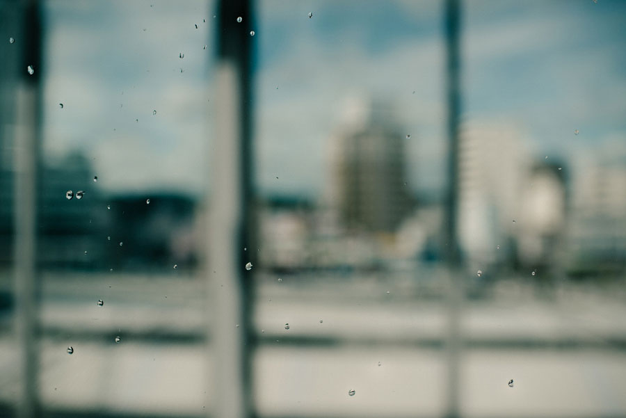 Raindrops on a window with a blurred Japanese cityscape in the background