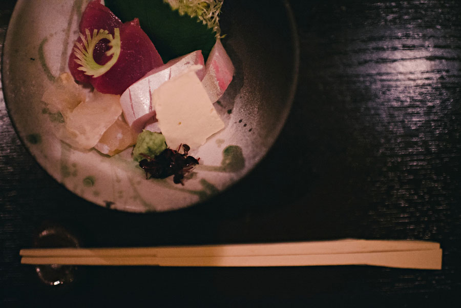 Sashimi platter with tuna, prawns, and wasabi served on a ceramic plate with wooden chopsticks
