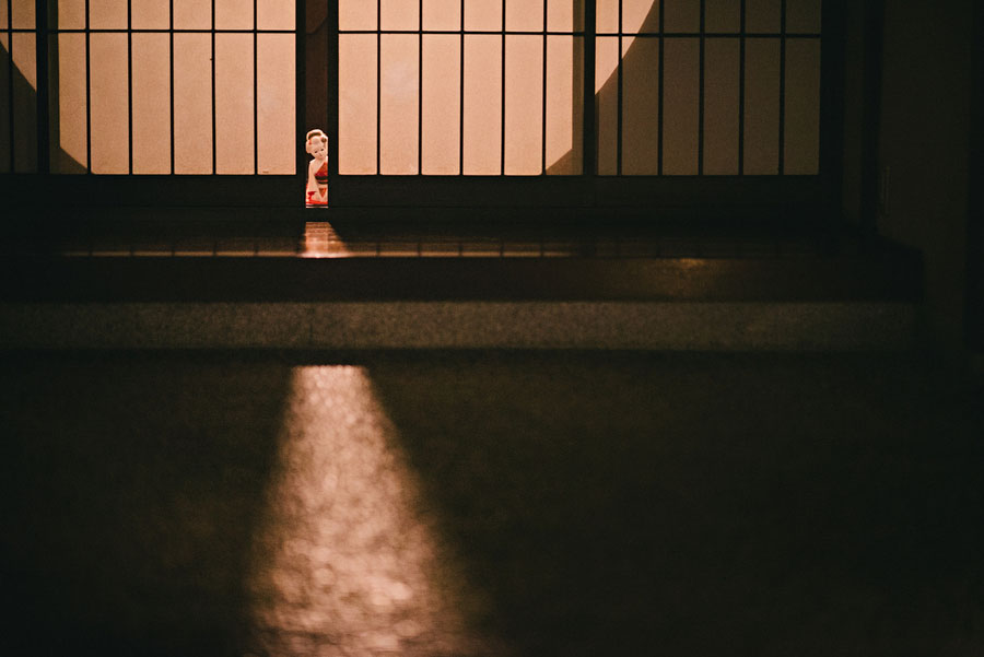 Small figurine silhouetted behind a sliding door with a triangle of light on tatami floor