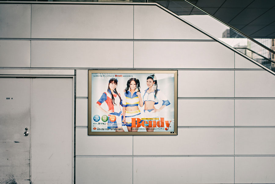 Japanese advertisement poster on a station wall featuring three women in colorful outfits